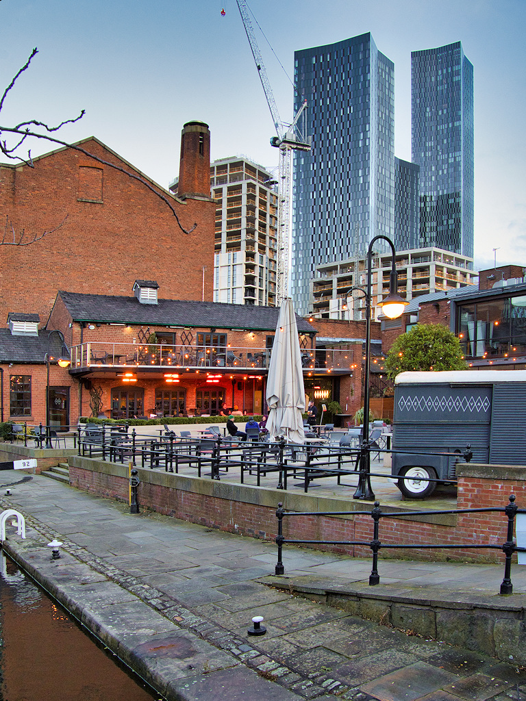 Castlefield canal basin in Manchester, with the Deansgate Square towers rising behind Victorian brick warehouses