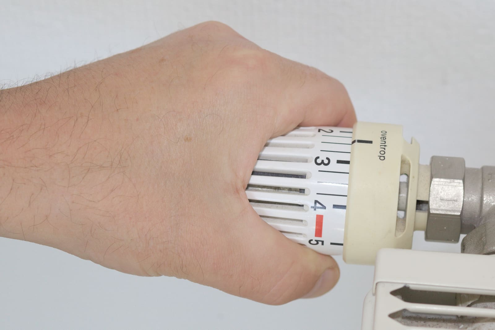 A hand turning down a thermostatic radiator valve