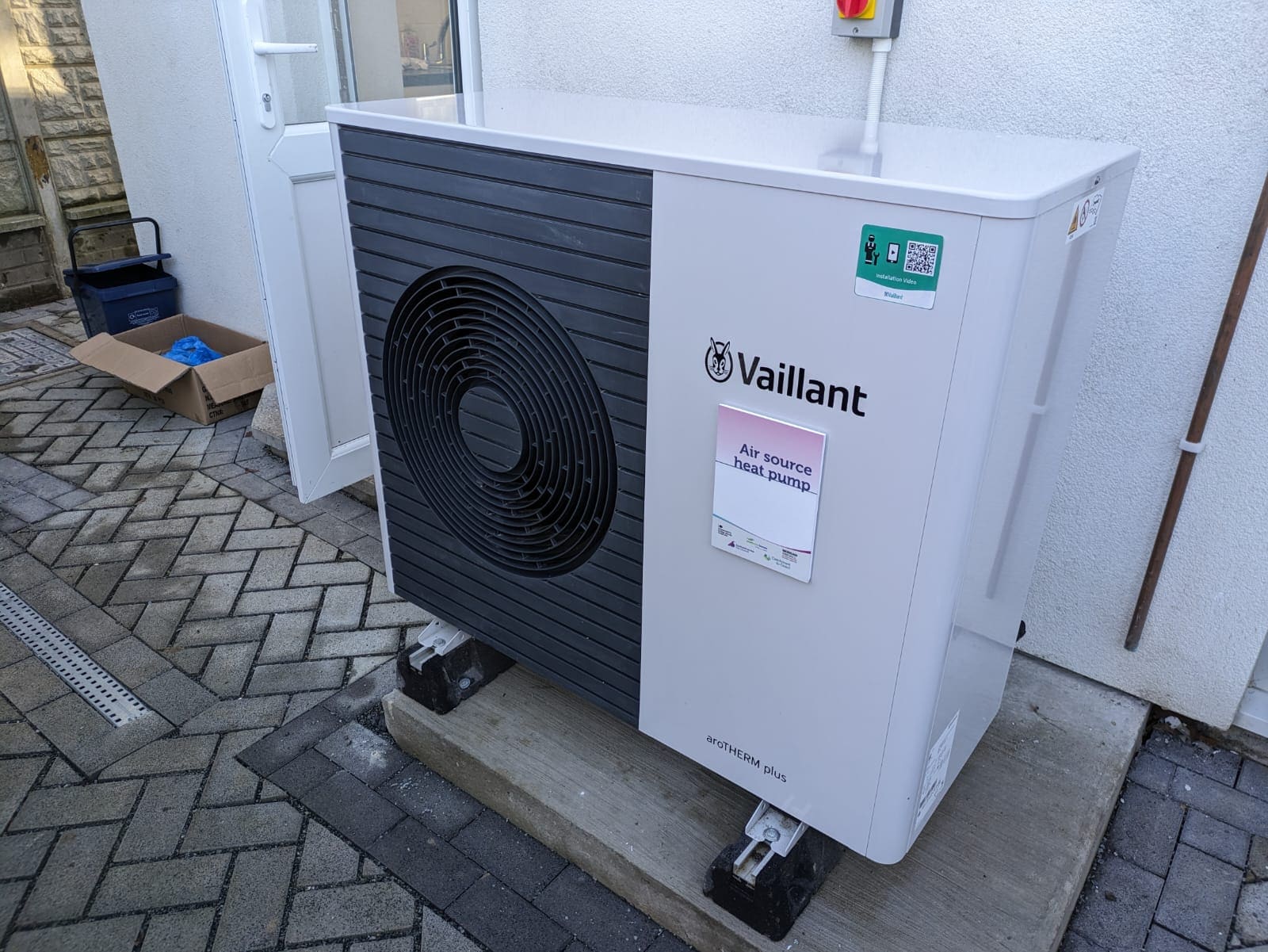 An air-source heat pump on the wall of a terraced house