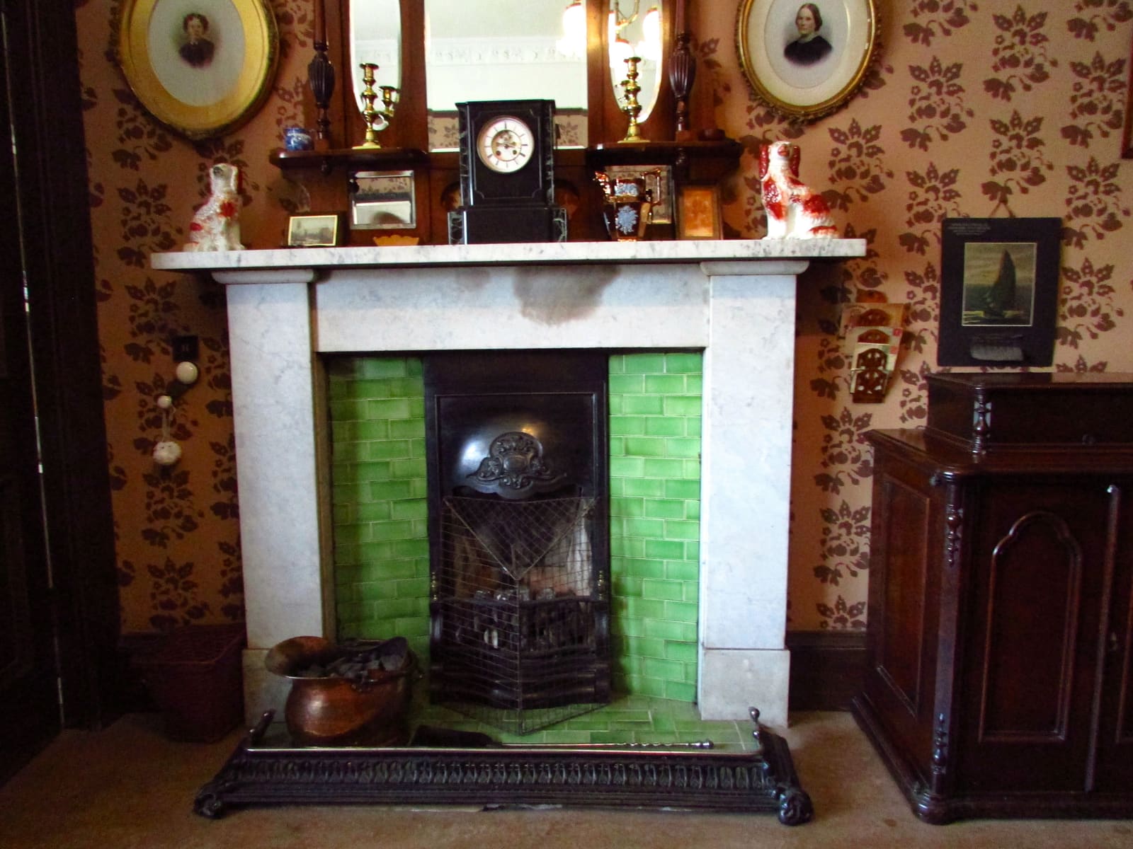 A period sitting room with a marble fireplace and green tiled surround