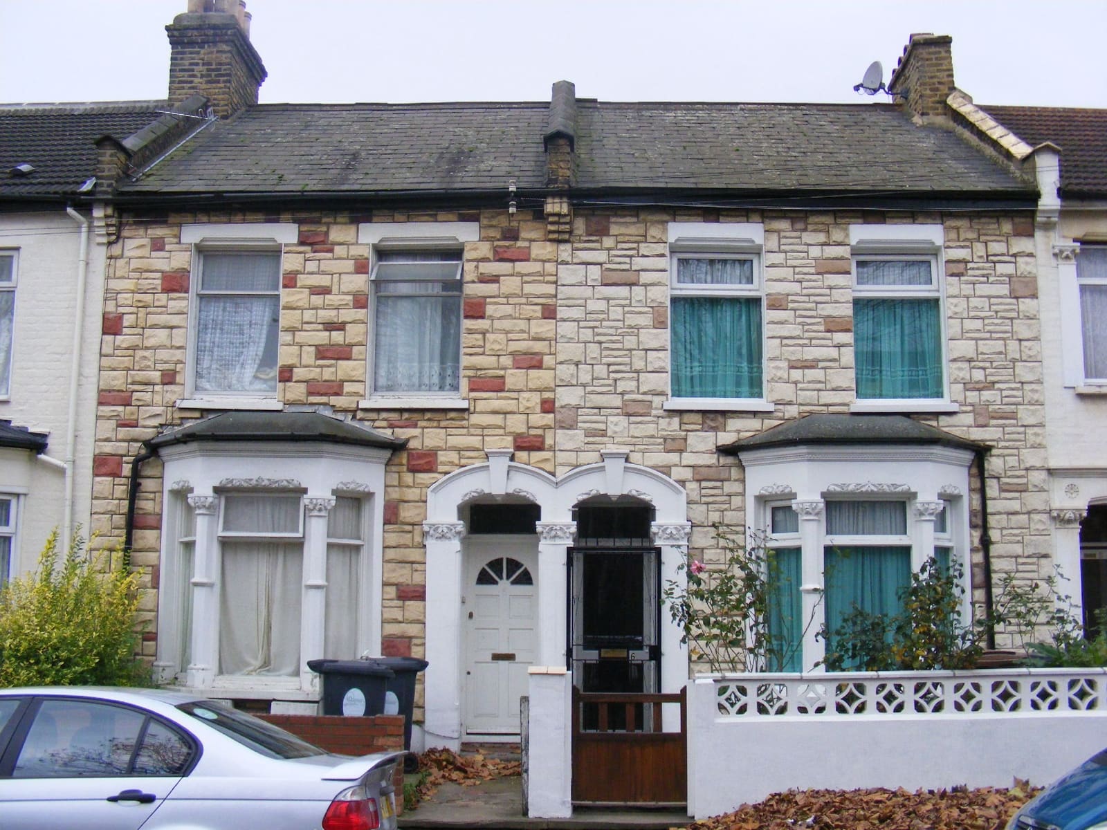 A pair of similar terraced houses, one stone-clad — the kind of alteration a survey flags
